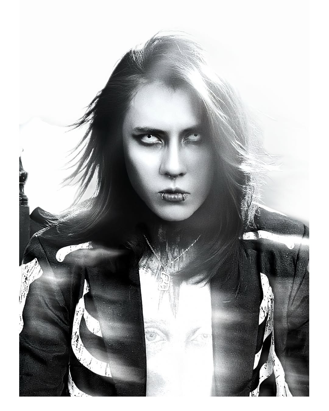 Johan Peraza in a high-contrast black and white dramatic portrait wearing a skeleton print jacket with gothic contact lenses