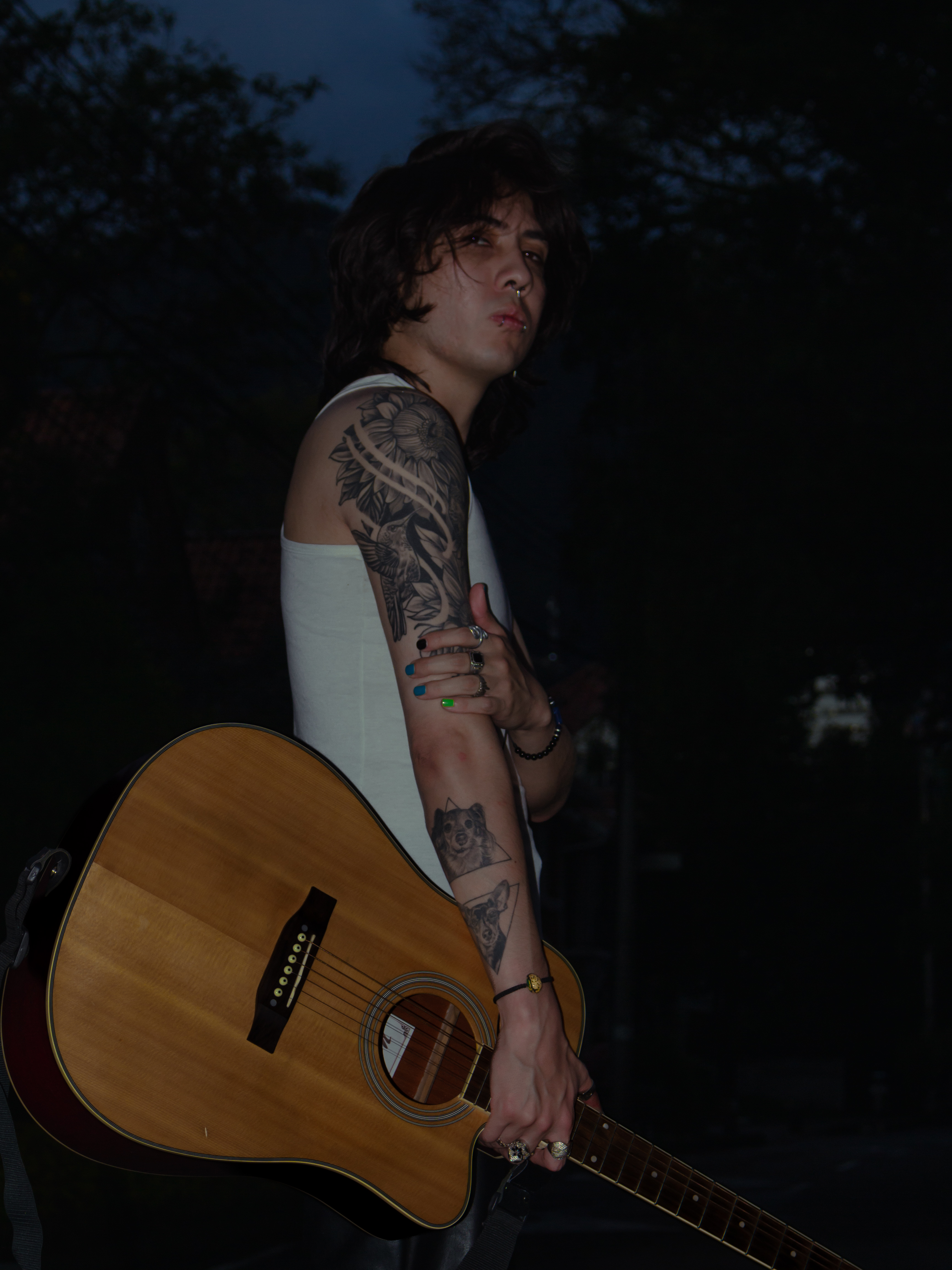Johan Peraza, side profile portrait with an acoustic guitar during an outdoor twilight photoshoot