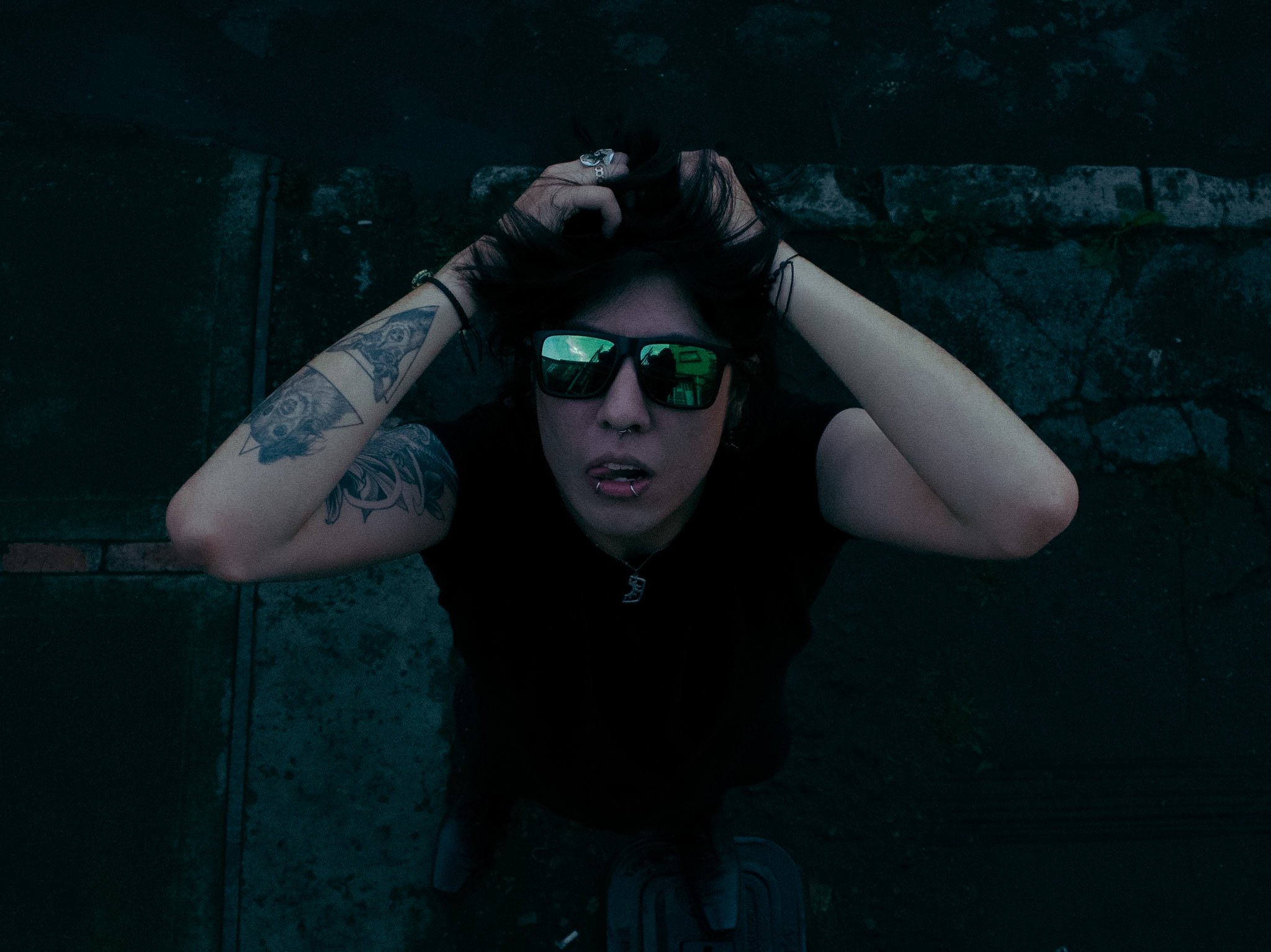 Johan Peraza, atmospheric close-up portrait wearing sunglasses in a dark moody setting