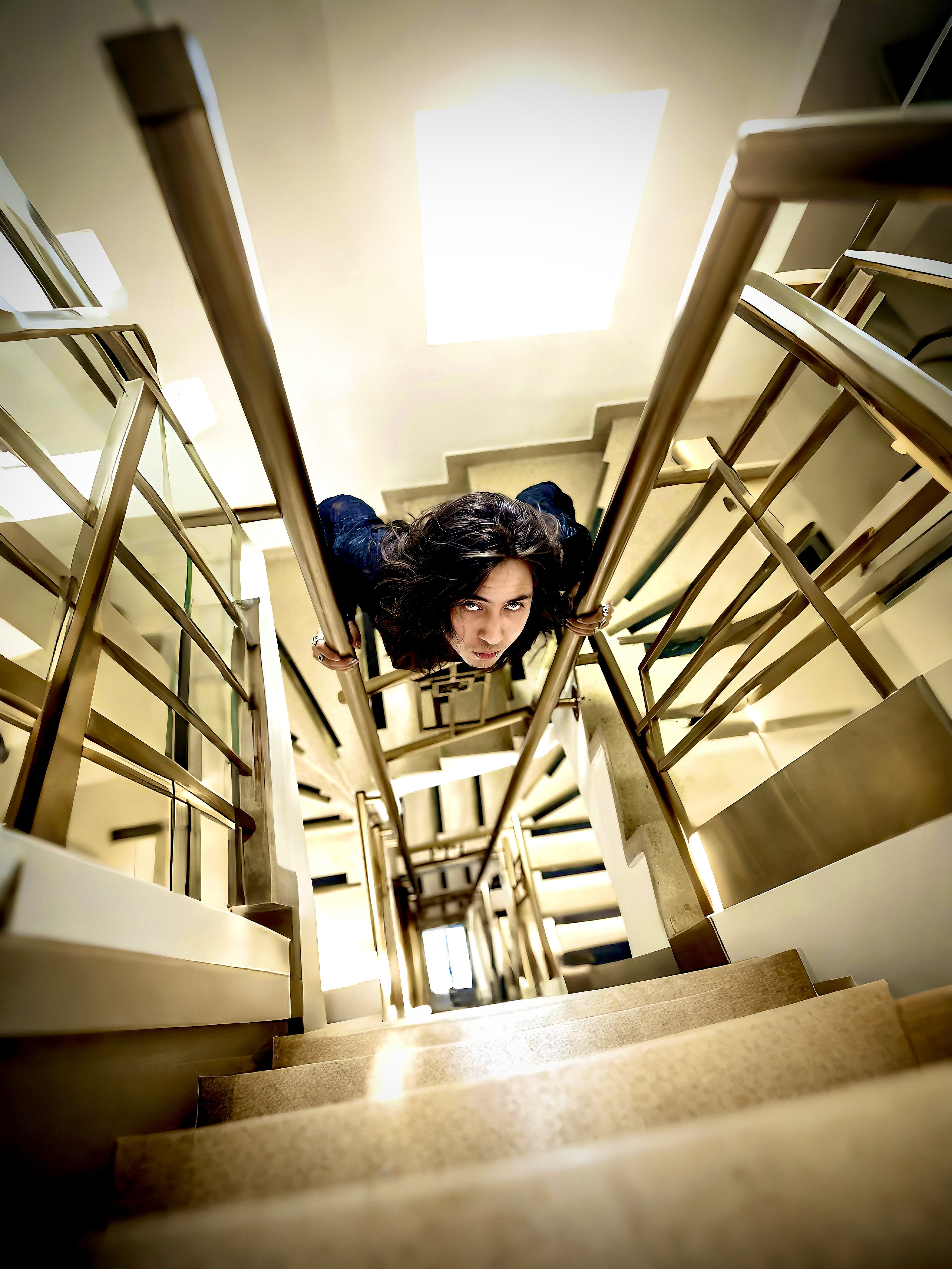 Johan Peraza, low-angle perspective looking down a bright symmetrical architectural staircase