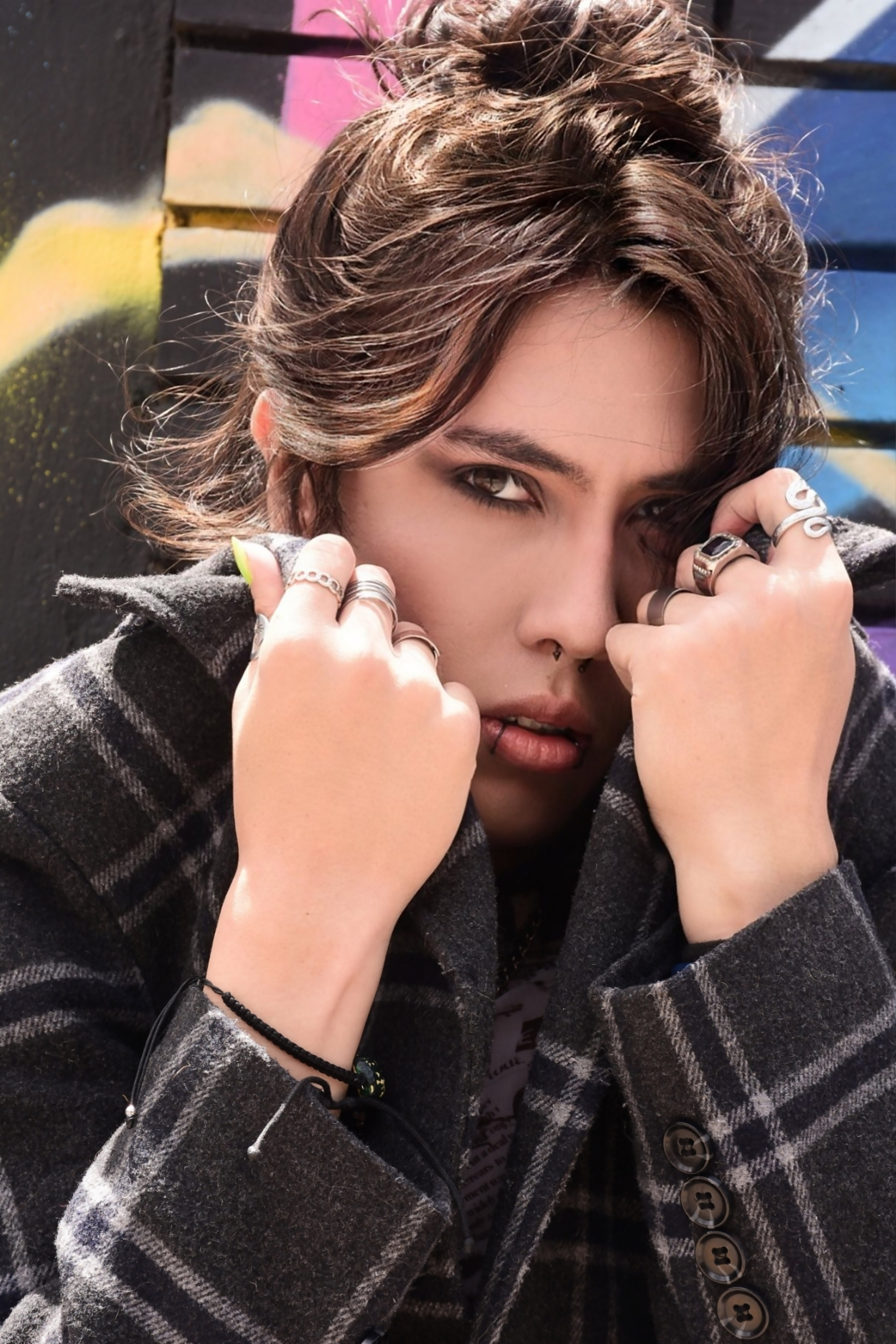 Johan Peraza, close-up high-fashion portrait wearing a checkered coat with hands near the face
