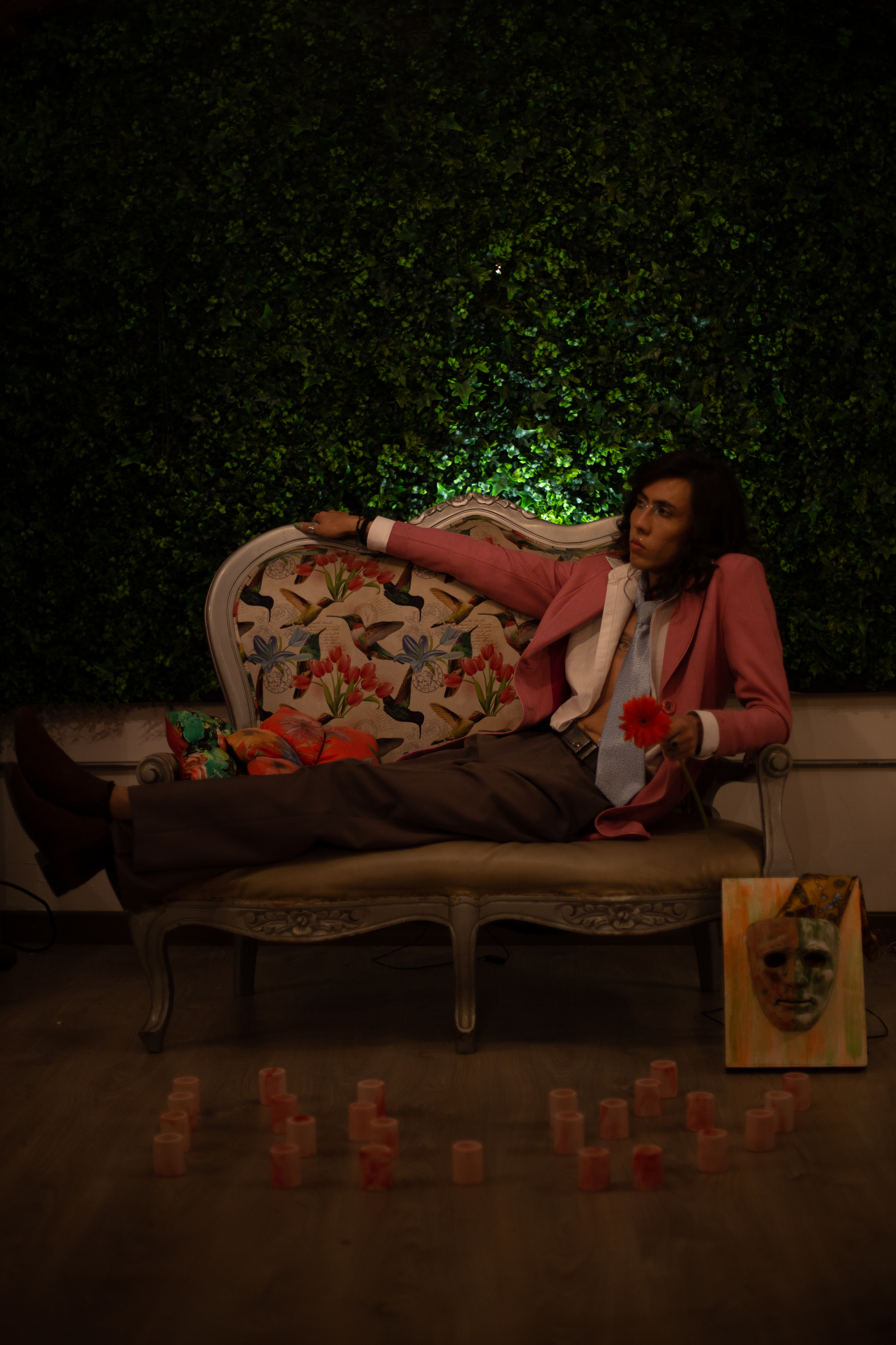 Johan Peraza, conceptual wide shot sitting on a vintage armchair against a dark green textured wall